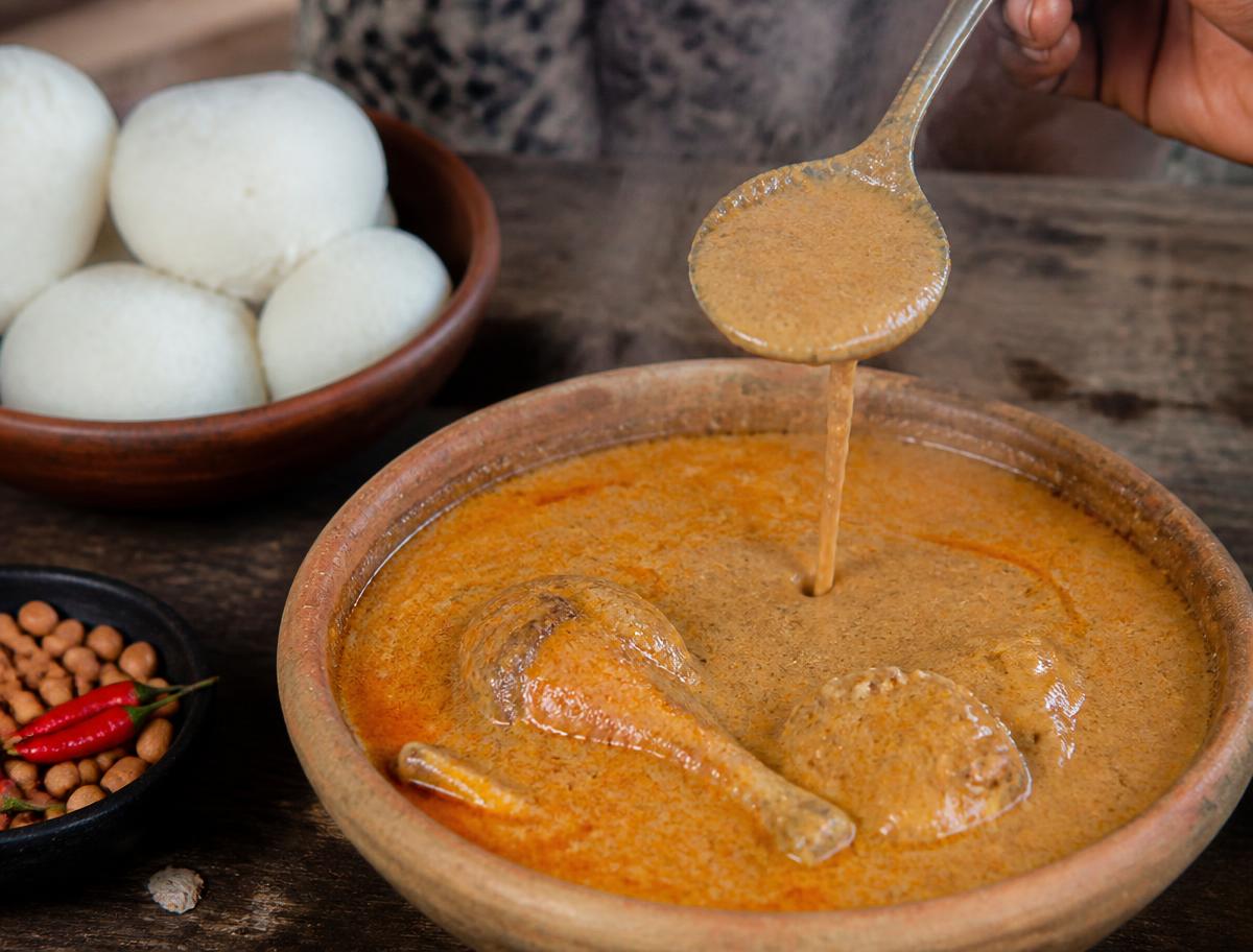 Creamy groundnut soup cooling in a bowl on a wooden kitchen table