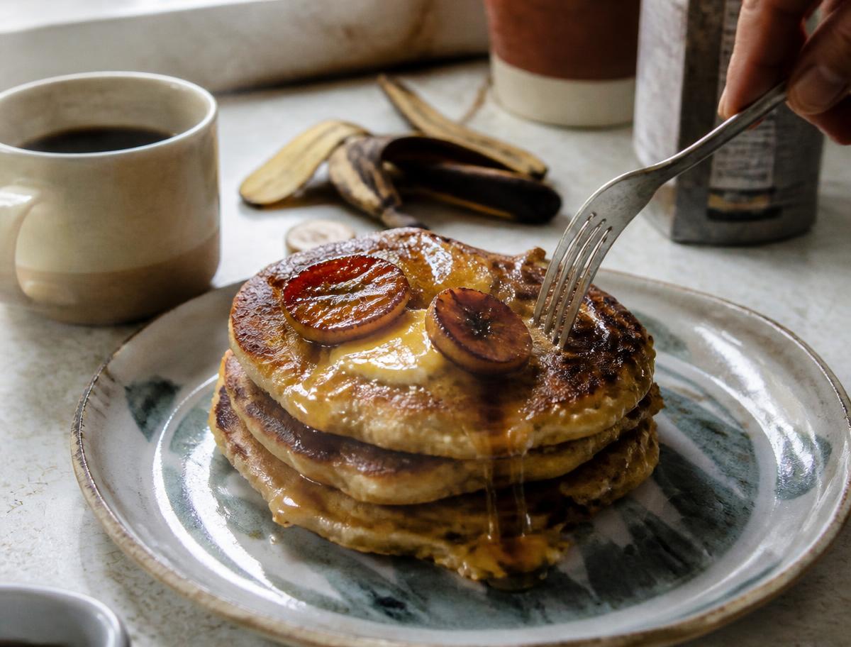 Stack of caramelized plantain pancakes on a sunlit kitchen counter