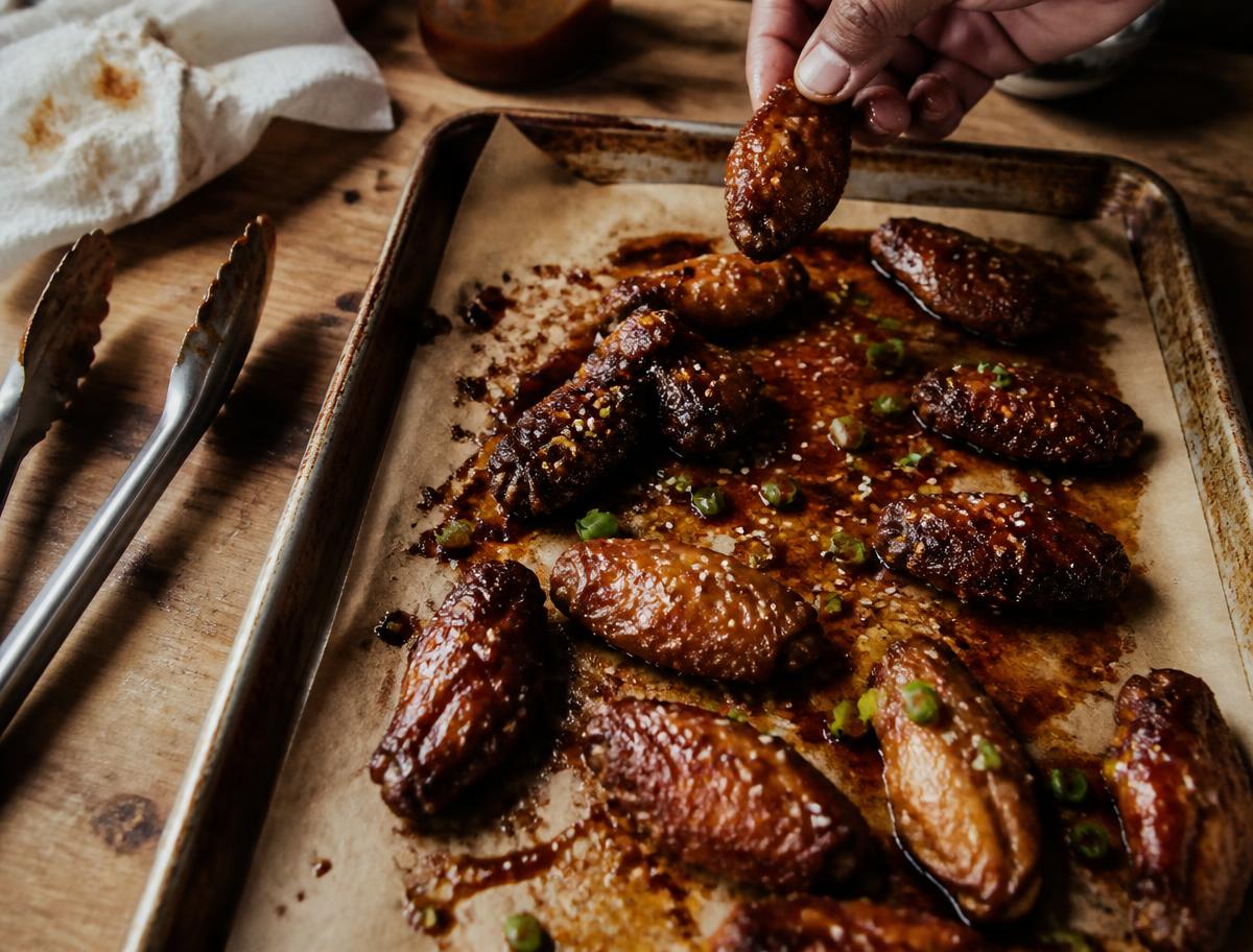 Crispy chicken wings glazed in dark red shito honey sauce with scallions